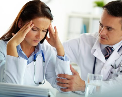 Portrait,Of,Woman,With,Headache,Touching,Her,Temples,With,Colleague